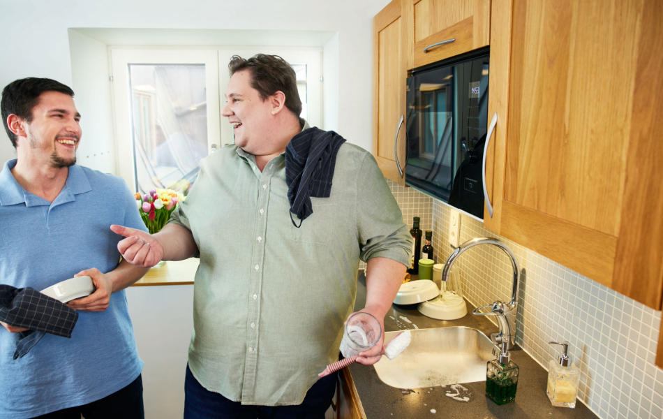 Two people chatting while doing dishes in a kitchen.